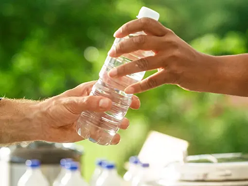 An image of passing a water bottle full of clean drinkable water